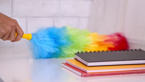 cleaning a table with a colorful feather duster