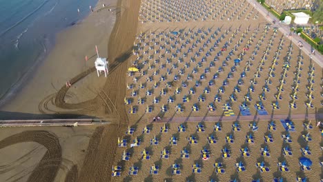 aerial drone view of vast miami south beach bustling with activity, featuring sea of parasols and sunbathers against backdrop of buildings during sunny summer day at florida, usa