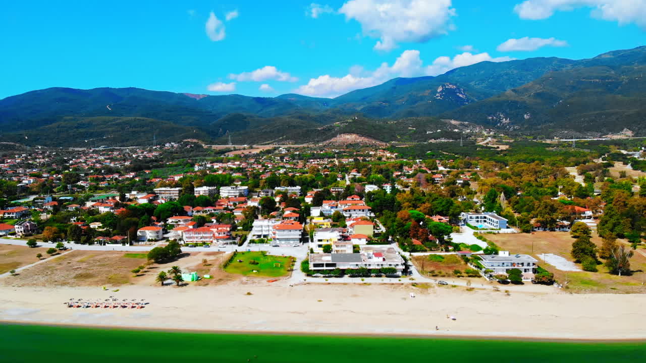 Panorama of the Asprovalta with multiple buildings and greenery, green hills on the background. Aegean sea coast. Sunny day. Greece