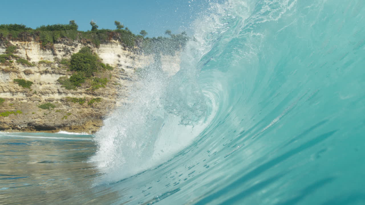 Turquoise waves roll against remote jungle coast in slow motion aerial view