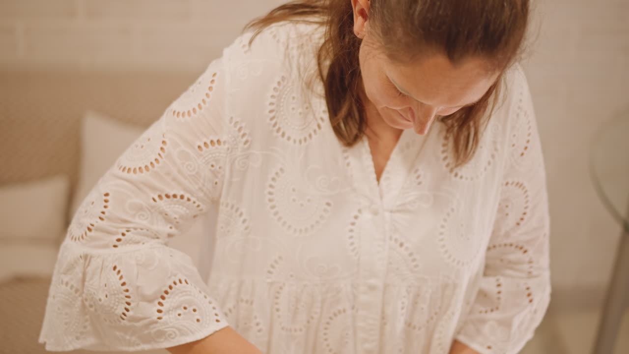 Donna chinata su una ciotola per impastare, che modella la crosta in una cucina luminosa, fornaia casalinga concentrata che liscia il bordo della torta, luce calda autunnale, delicata camicetta di pizzo, movimento calmo e attento, primo piano di una zucca artigianale