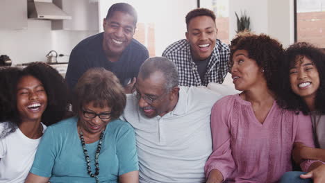 multi generation black family sit relaxing together at home smiling to camera, close up