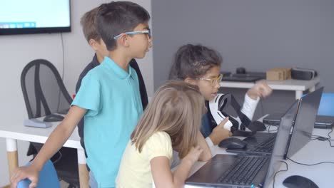 Group-of-serious-schoolchildren-sitting-and-standing-at-desk