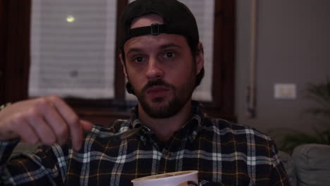 slow motion of caucasian man that eats ice cream on the sofa, in front of tv, in his leisure