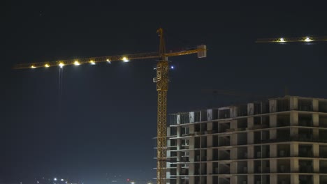 construcción por la noche. lapso de tiempo. grúa torre en un sitio de construcción con iluminación