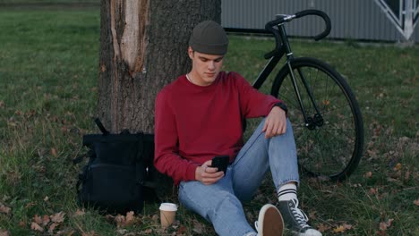 young man relaxing in park with bicycle