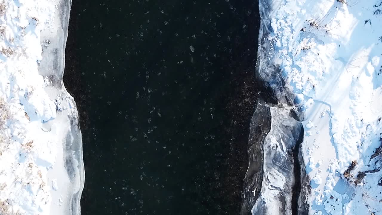 slow aerial dolly top down on Elkhorn creek frankfort kentucky with large chunks of ice floating down the river and snow on the banks