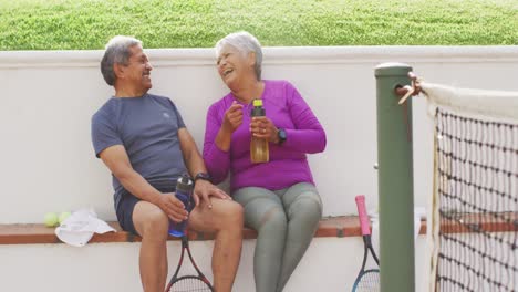 Video-of-happy-biracial-senior-couple-embracing-and-talking-after-match-on-stands