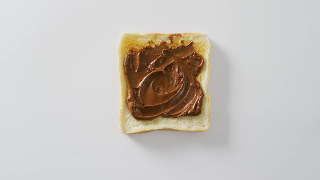 Vidéo en gros plan d'un toast à la pâte à tartiner au chocolat sur fond blanc