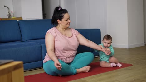 plus size woman disturbed by her baby while sitting on the floor in meditation