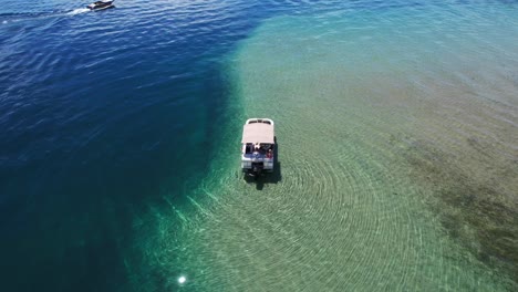 A-pontoon-boat-is-anchored-on-the-edge-of-the-drop-off-at-Detroit-Point-on-Higgins-Lake,-Roscommon,-MI-2