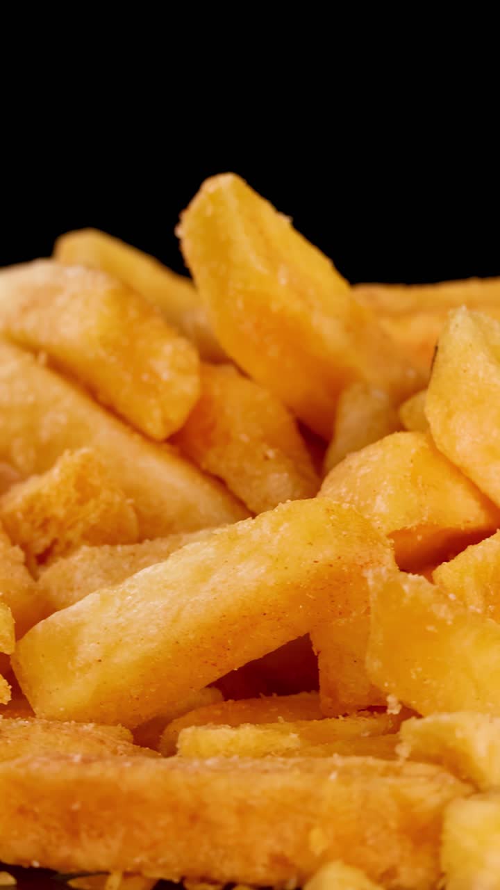 Batatas fritas douradas giram sob iluminação de estúdio, destacando a textura crocante e detalhes apetitosos.