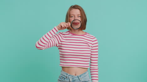 woman holding magnifier glass loupe on teeth looking at camera showing funny smiling face mouth