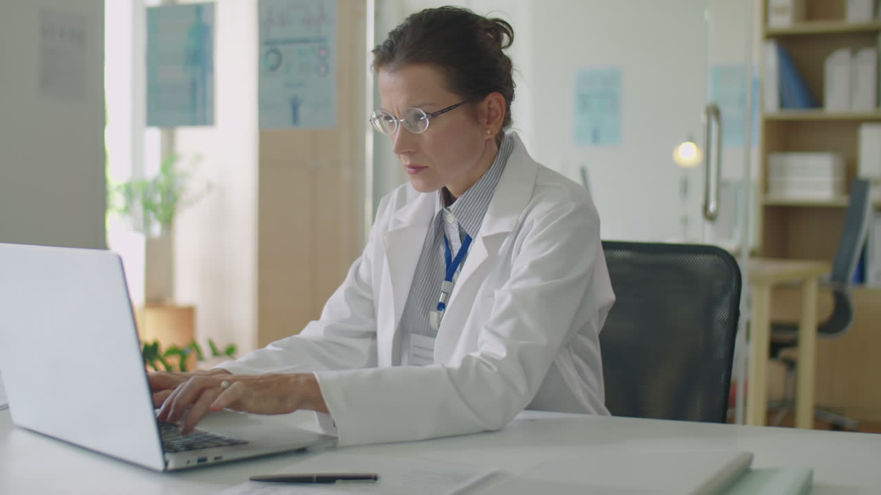 Female Doctor Typing on Laptop at Office Desk