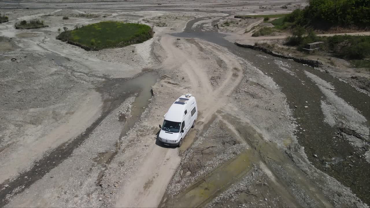 Drone shot of white van passing in campspot at river