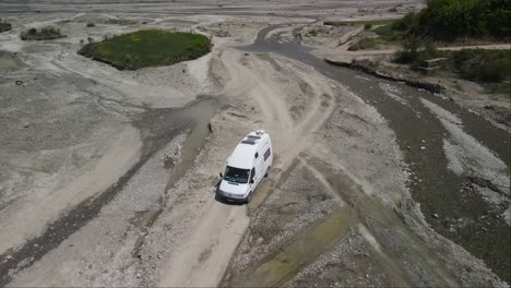 Drohnenaufnahme-Eines-Weißen-Lieferwagens,-Der-Am-Campingplatz-Am-Fluss-Vorbeifährt