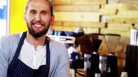 Portrait-of-smiling-waiter-leaning-at-counter