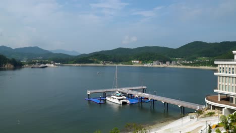 ferry boat on dock in front of belvedere hotel in geonje south korea - wide shot