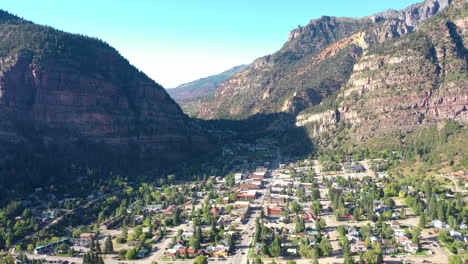 imágenes aéreas de drones de la ciudad montañosa de ouray colorado, autos conduciendo por el centro y casas rodeadas de acantilados rocosos de montaña y sombras proyectadas por la ciudad