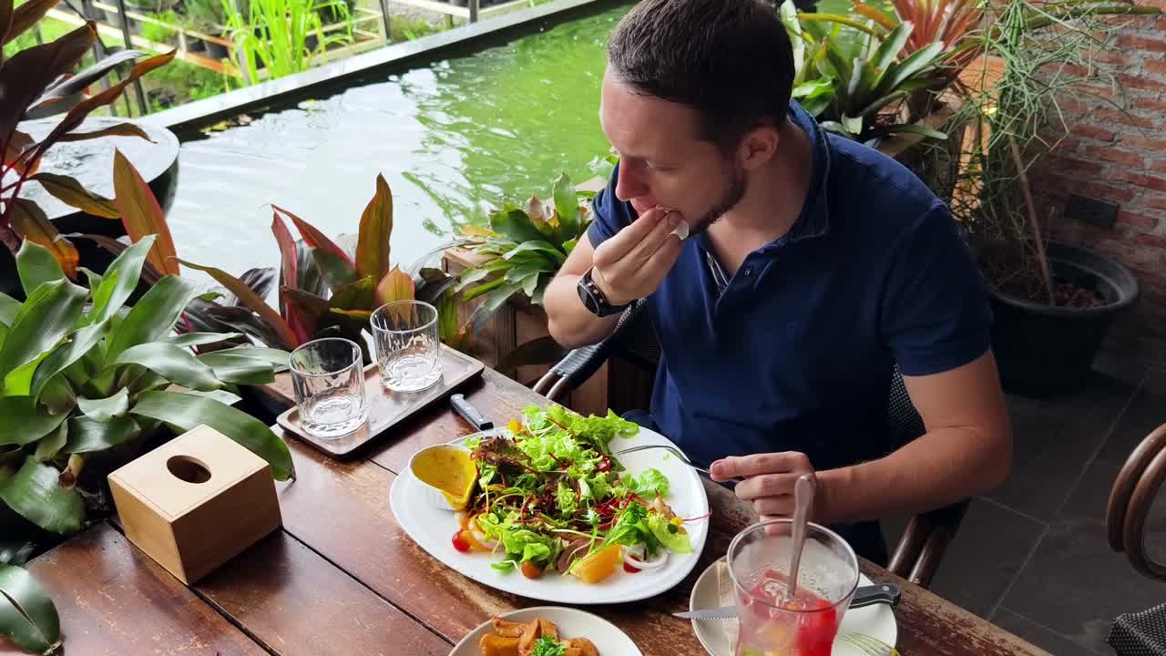 hombre disfrutando de una ensalada saludable en un hermoso restaurante al aire libre