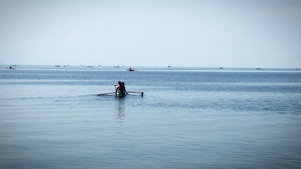 Anglers and small-fry fishermen on tiny rowboats go about finding their daily catch to bring to market at a fishing town in the Visayas region of the Philippines.