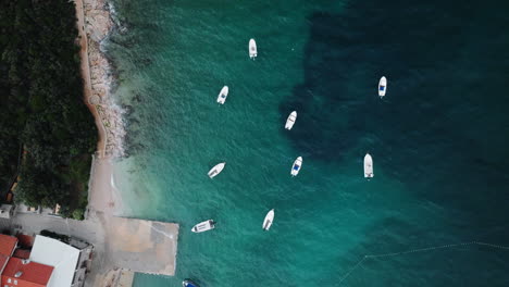 small boats anchored offshore of slatina beach bob in turquoise blue water