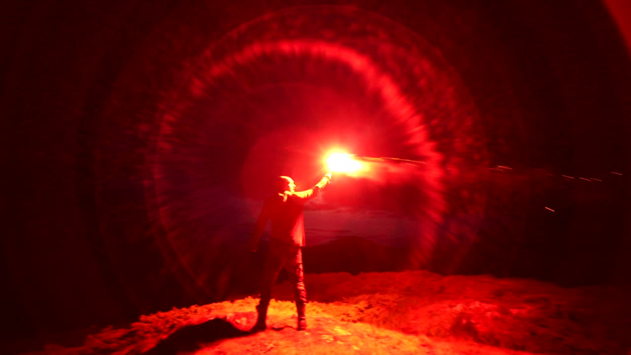 밖에서 서 있는 오렌지색 불꽃놀이 막대기 를 가진 사람