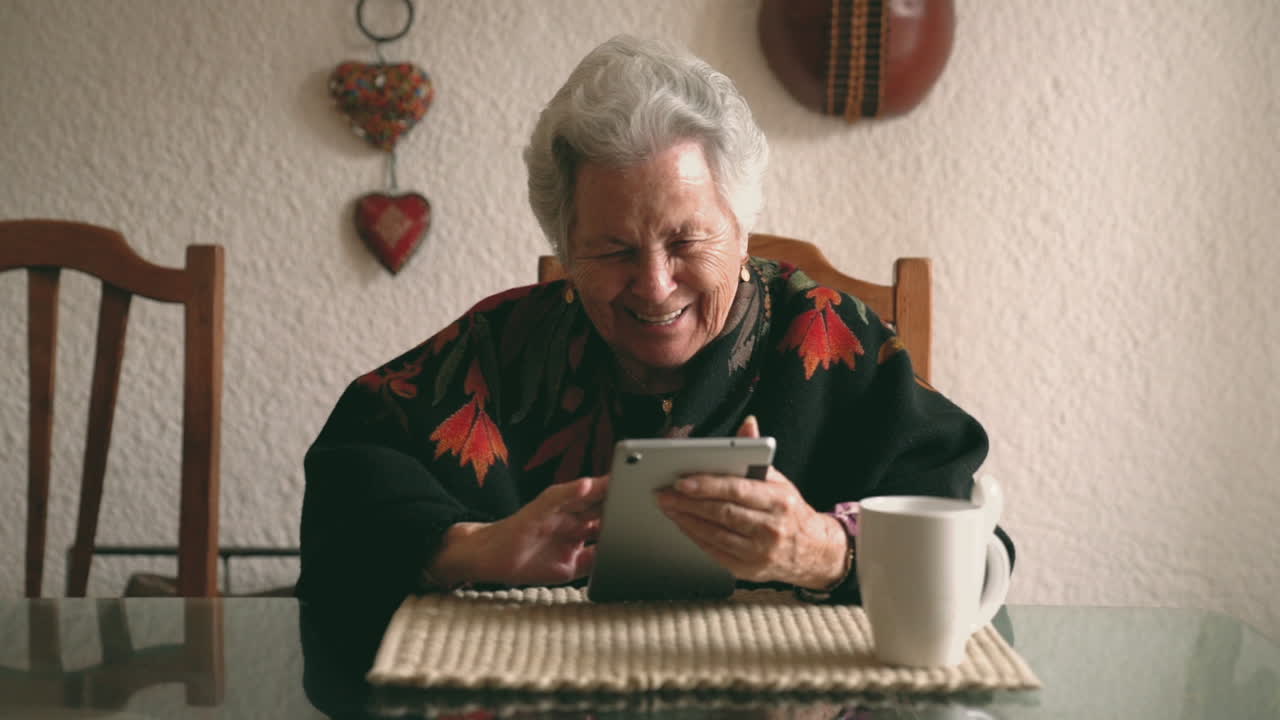 Aged woman with gadget sitting at table