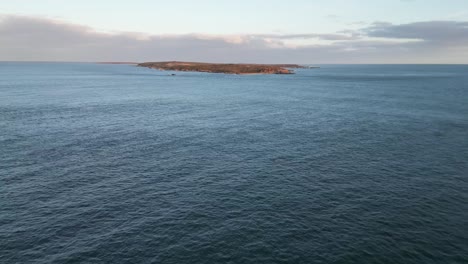 a fly over of mira bay from scatarie island, flying towards a small town over looking the ocean