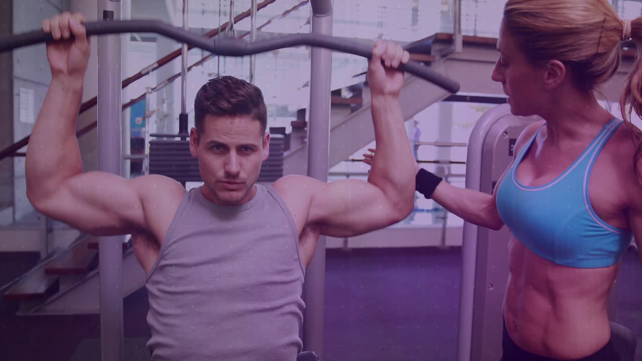 Male client gripping bar while coach adjusting wrist doing pulldown reps for health HUD tracking