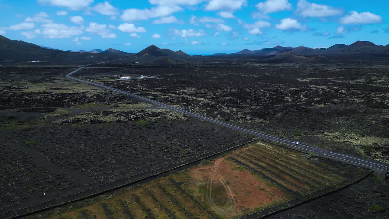 Imagens de uma estrada reta atravessando campos dramáticos de lava vulcânica preta em La Geria, Lanzarote, Ilhas Canárias, com montanhas e céu azul