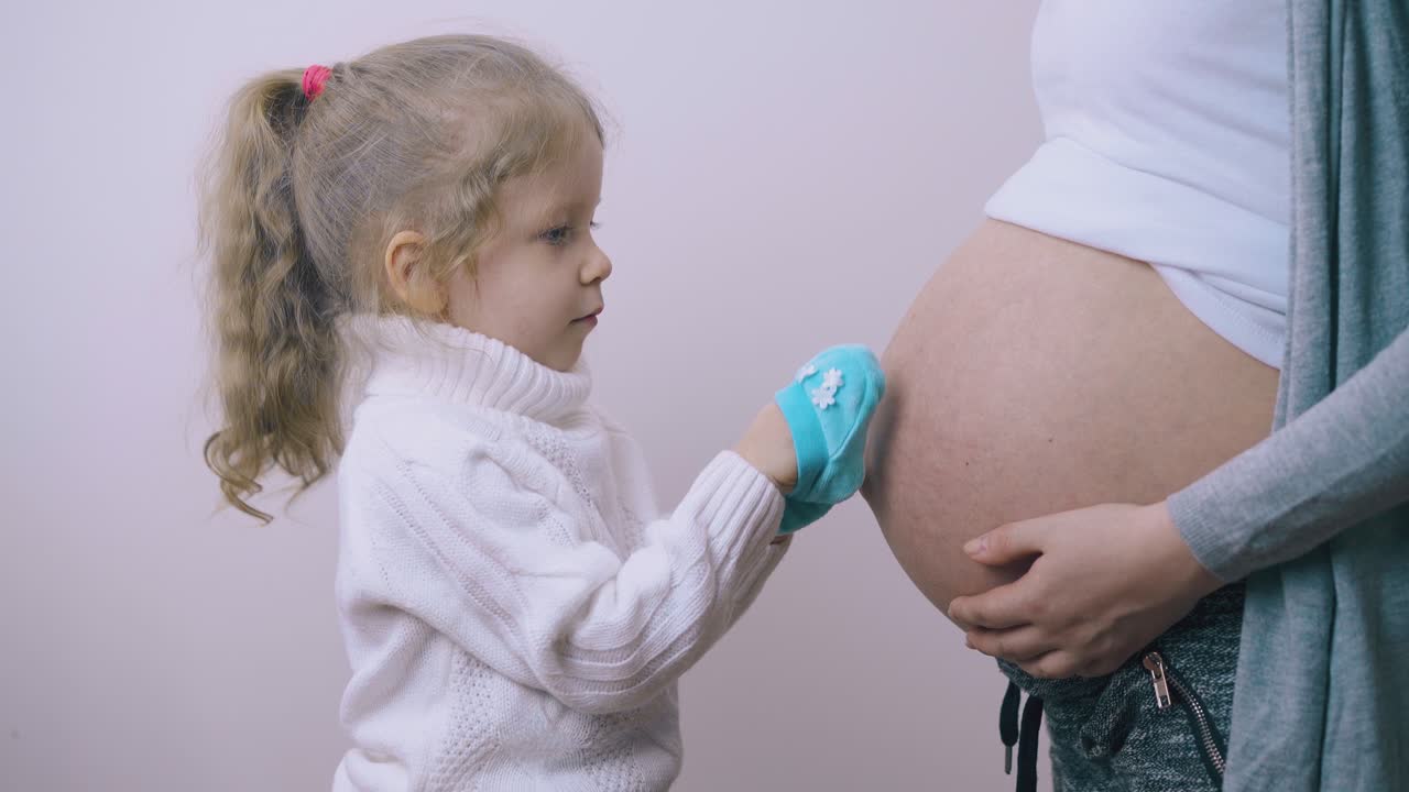 la ragazza mette le scarpette blu sulle palme con la mamma incinta.