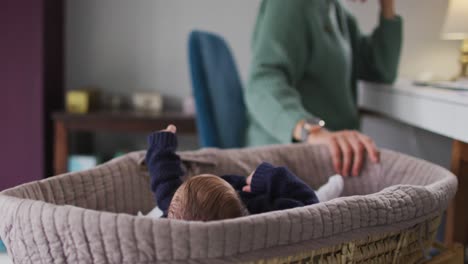 video de una madre caucásica trabajando en una computadora portátil desde casa con un bebé recién nacido