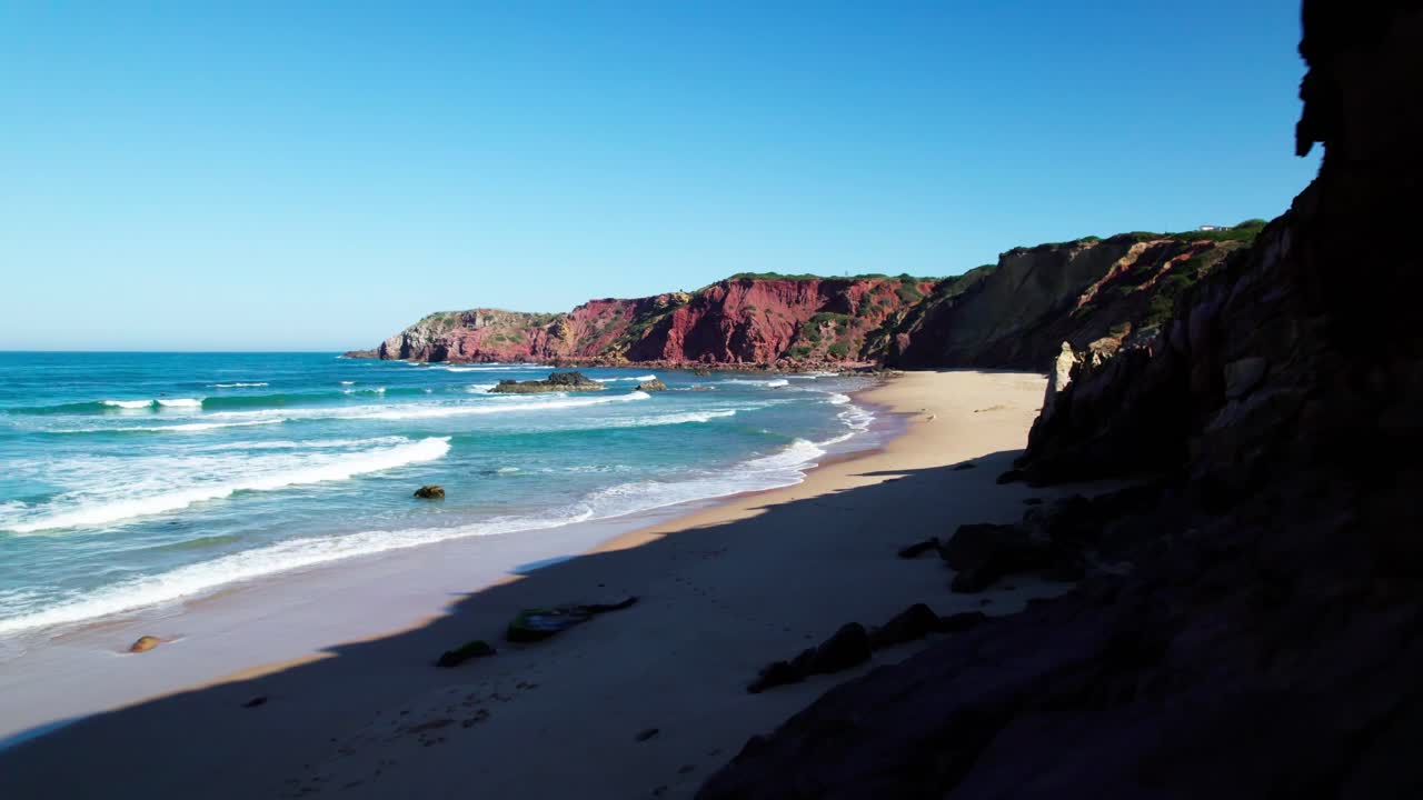 Scogliere rocciose e spiaggia con mare mosso in una soleggiata giornata estiva. - ripresa aerea