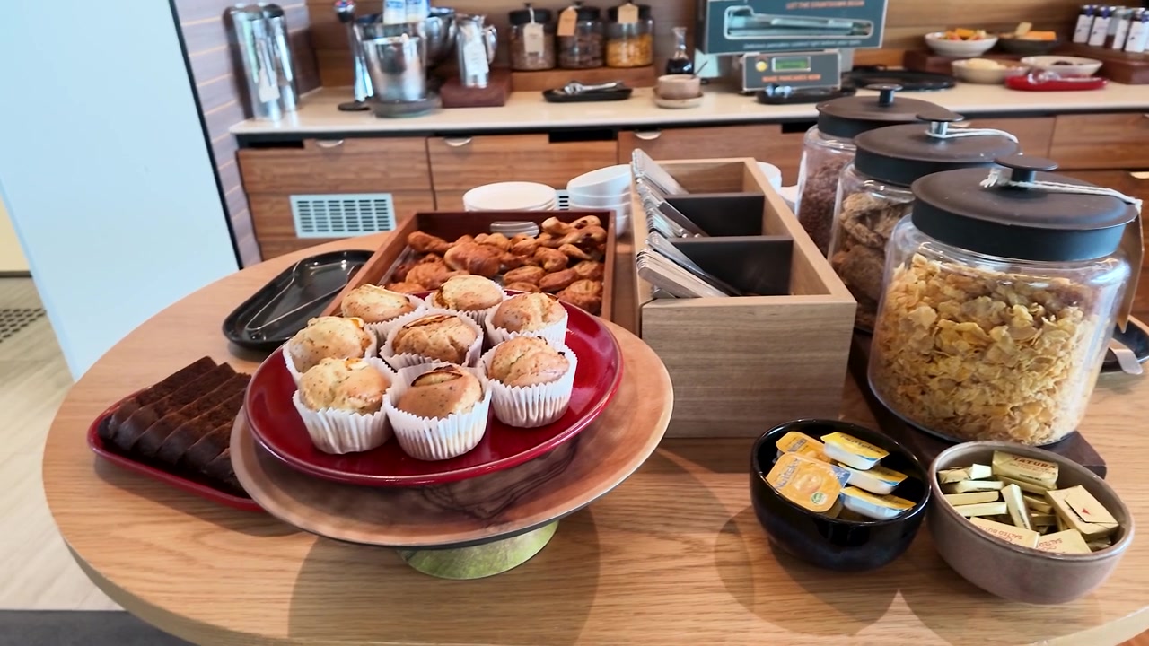 Un paneo lento de cámara por un bufé de desayuno de hotel con magdalenas, cruasanes y cereales.