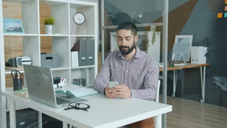 man working on laptop and smartphone in modern office