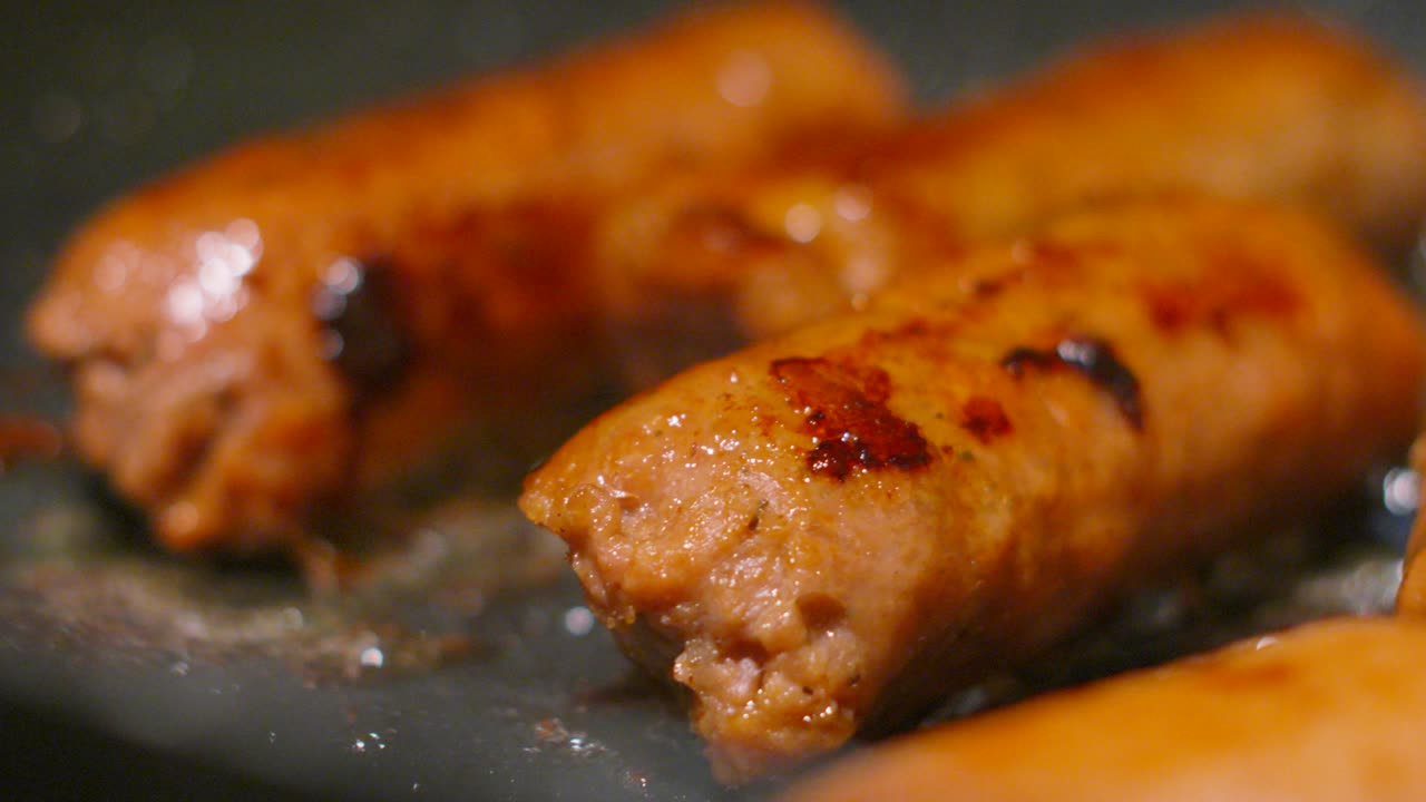 Close Up of Collection of Vegan Sausages Cooking in Bubbling Hot Oil Cooked in Frying Pan. Plant Based Tasty Meatless Food Full of Protein. Healthier Lifestyle Choice