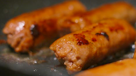 close up of collection of vegan sausages cooking in bubbling hot oil cooked in frying pan. plant based tasty meatless food full of protein. healthier lifestyle choice