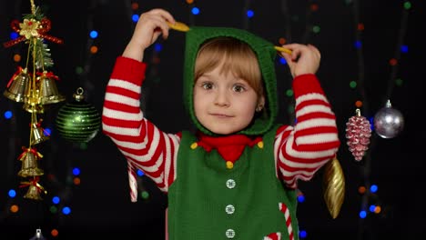 kid girl in christmas elf santa helper costume dancing, fooling around. new year holiday celebration