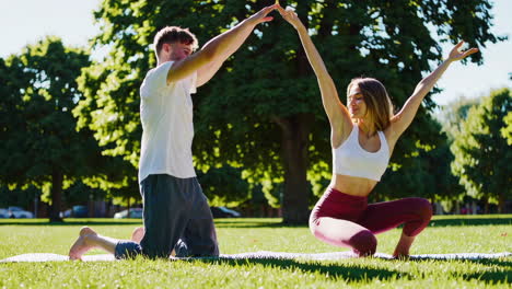 una pareja practicando yoga en un parque.