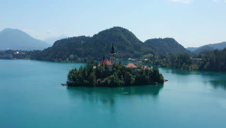 church of mary the queen surrounded with green forest at the isle in the lake bled, slovenia