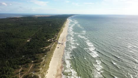 aéreo: volando hacia atrás sobre la majestuosa playa de nida con bosque y mar