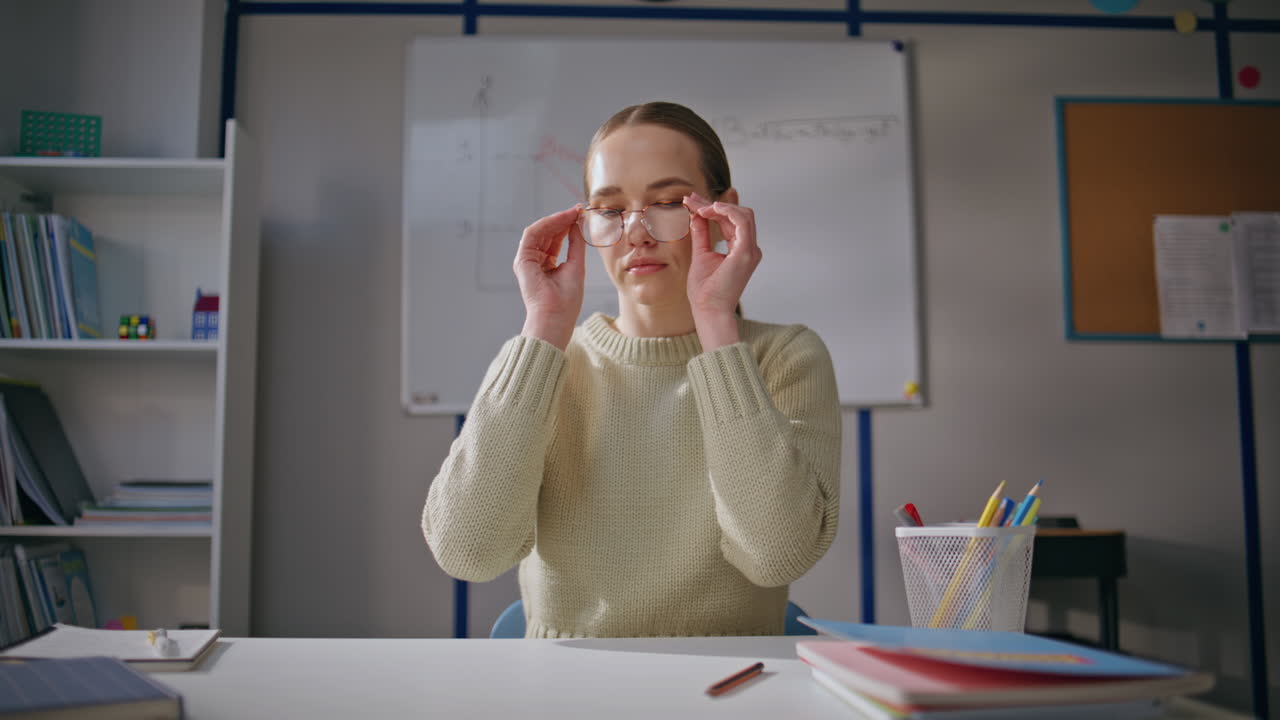 Focused educator ending work at school closeup. Teacher lady taking off glasses