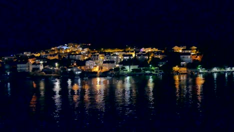 night view of a coastal village with lights reflecting on the water