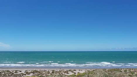 Flying-parallel-to-beach-and-beautiful-turquoise-ocean-on-a-windy-spring-day---Waikuku-Beach,-Pegasus-Bay