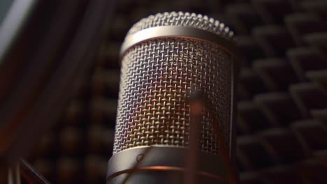 primer plano de un micrófono de estudio con protección contra explosiones y pantalla de sonido a su alrededor