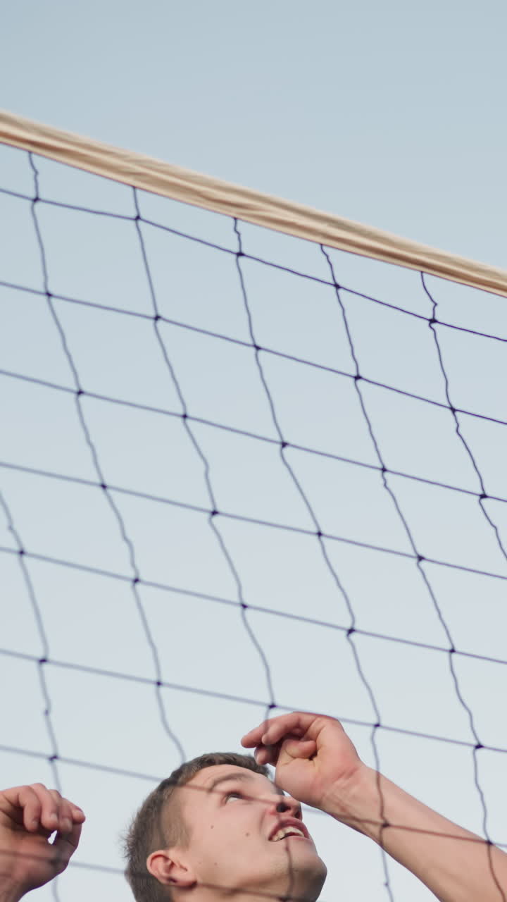 선수가 높이 뛰어내려 볼리볼을 네트 위로 아내며 힘과 정밀성을 보여주고, 밝은 하늘과 스포츠 구조는 역동적인 스포츠 환경을 만니다.