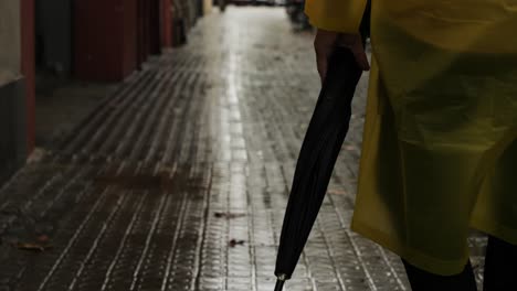 business man tourist person with umbrella and raincoat on rainy european city street, lights reflecting, walking in barcelona or amsterdam during the rain