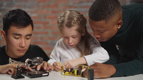 girl and black engineer work with chip asian guy fixes disk