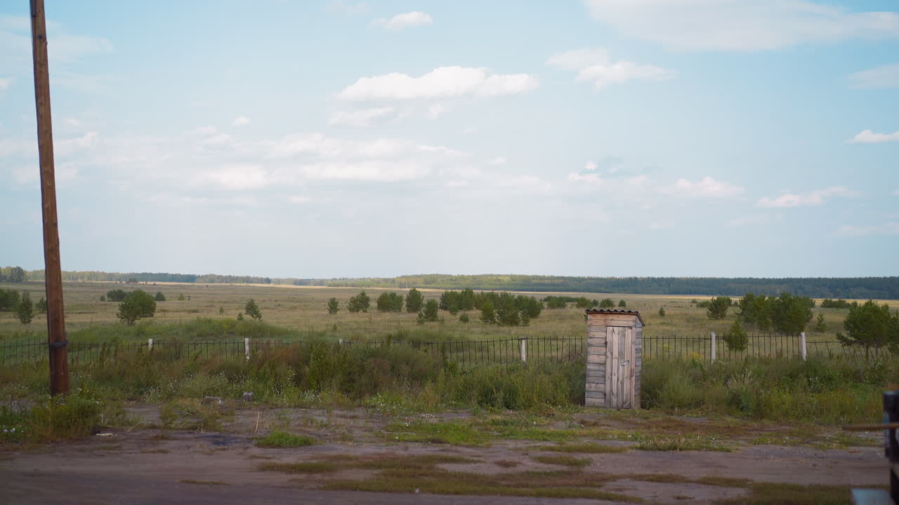 baño de compostaje de madera solitario cerca de la valla en el patio de la casa del pueblo